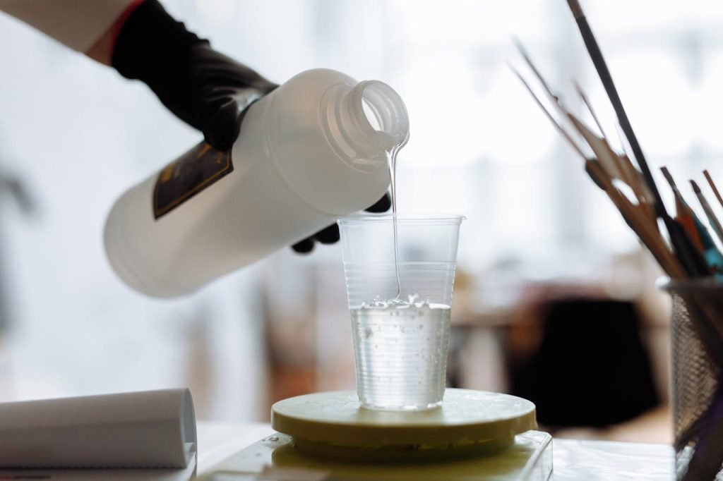 Close-up of liquid resin being poured into a plastic cup indoors.